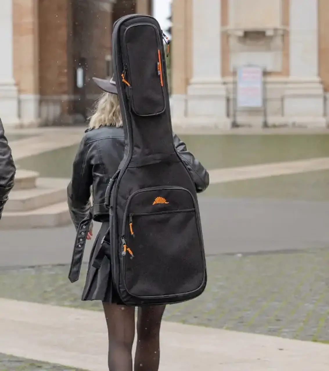 bassista trasporta con una custodia morbida Tobago il suo basso elettrico per andare a fare un concerto in una piazza