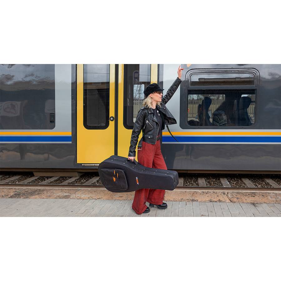 A guitar player traveling by train with their guitar in a TOBAGO semi-rigid case.